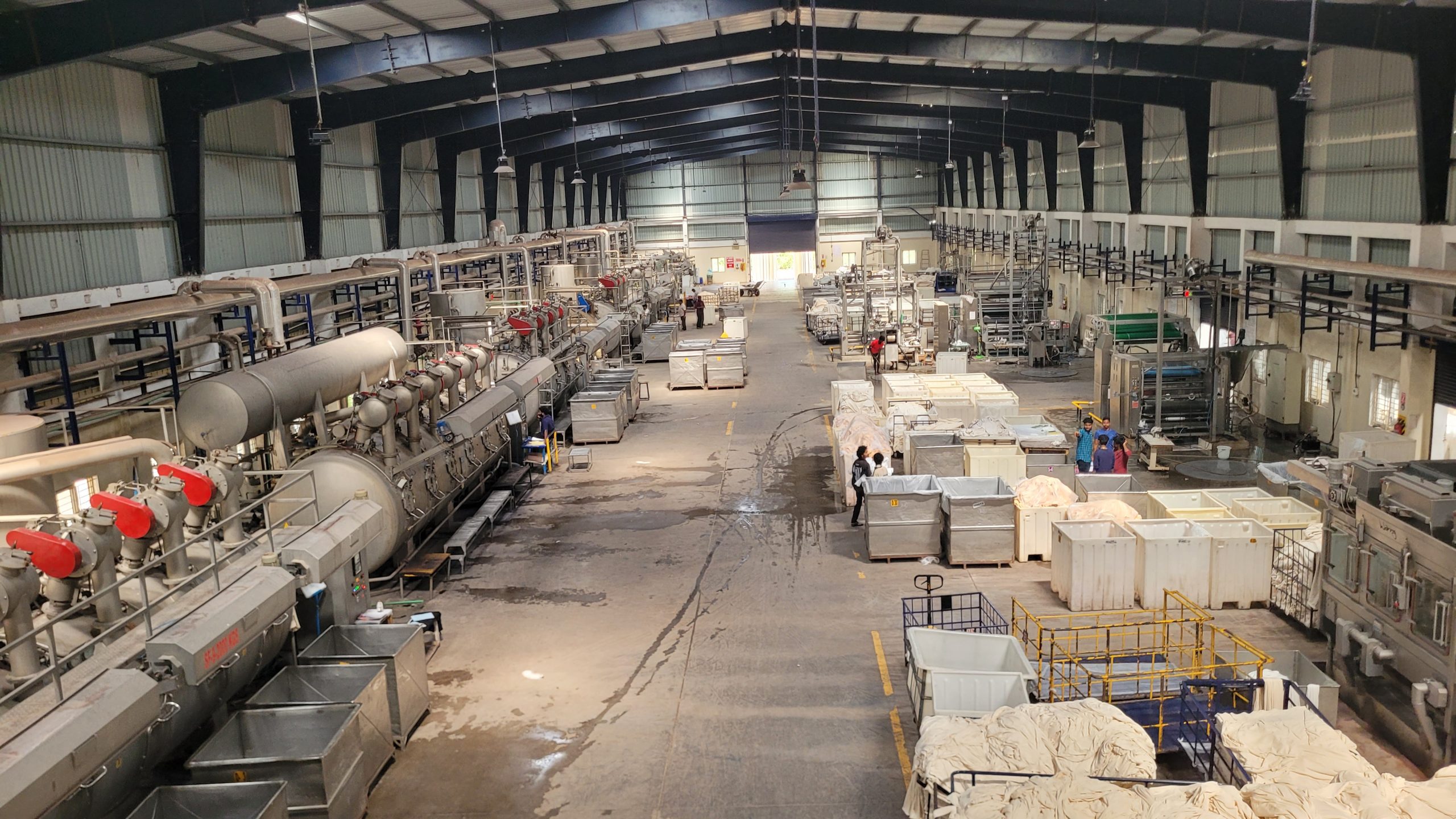 Inside the textile dyeing facility featuring industrial high-pressure jet dyeing machines and large-scale fabric processing units for professional garment manufacturing.